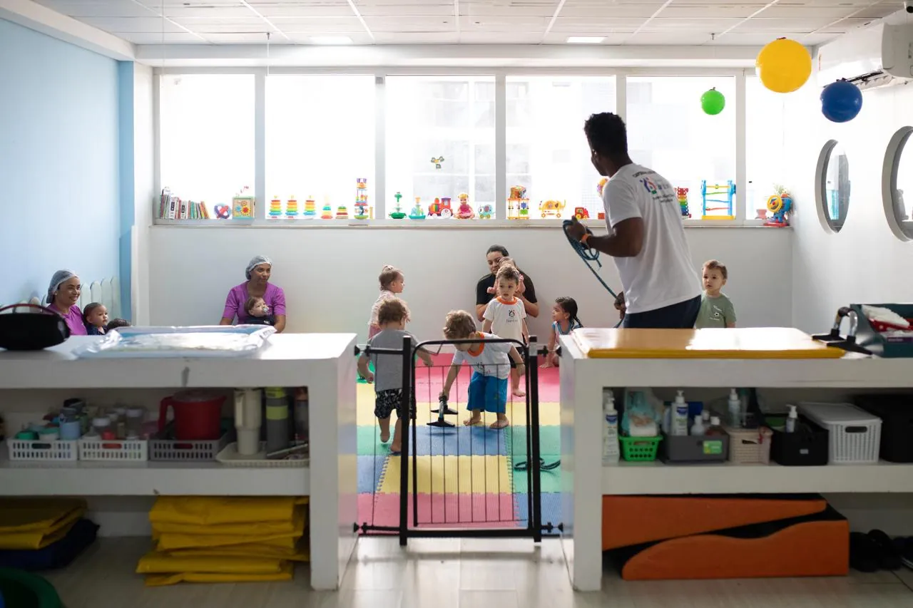 Sala ampla e iluminada com materiais pedagógicos e crianças em atividade