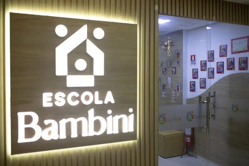 Fachada iluminada da Escola Bambini com o letreiro da marca