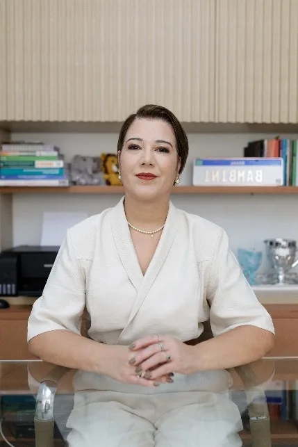 Luana, gestora da Escola Bambini, sentada à mesa da direção